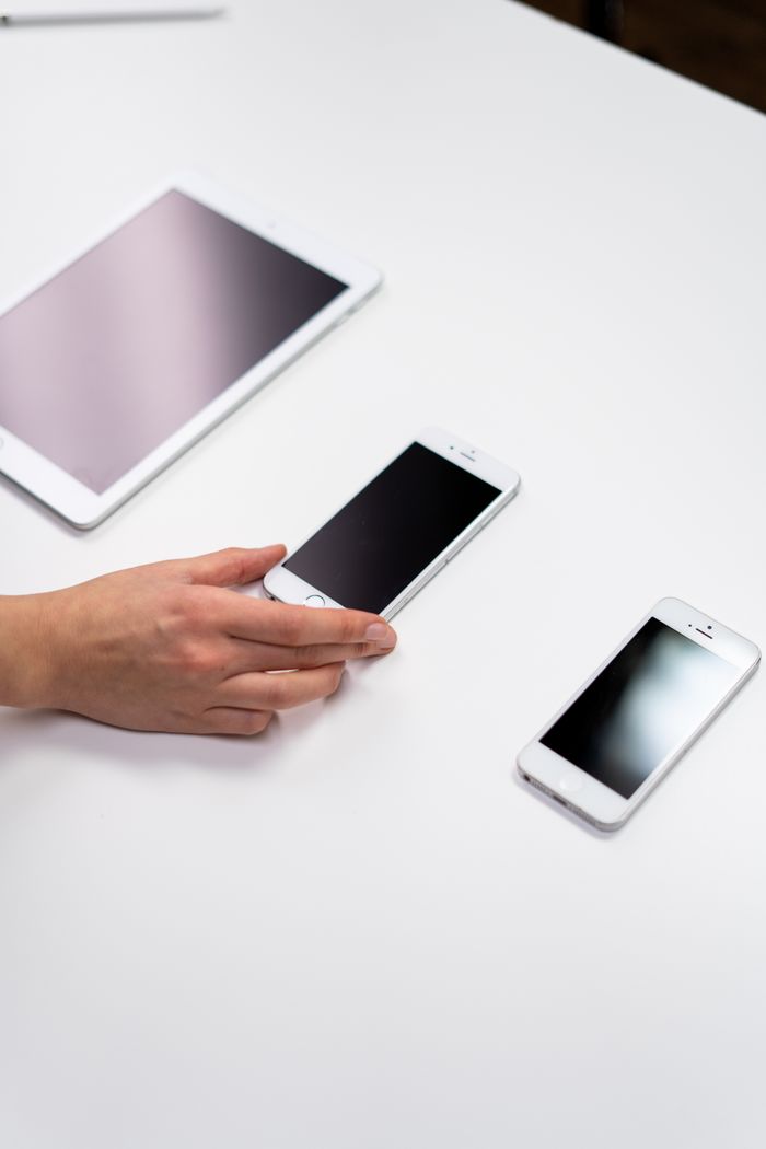 about-02 Top view of a minimalist setup featuring a tablet and smartphones on a white surface.