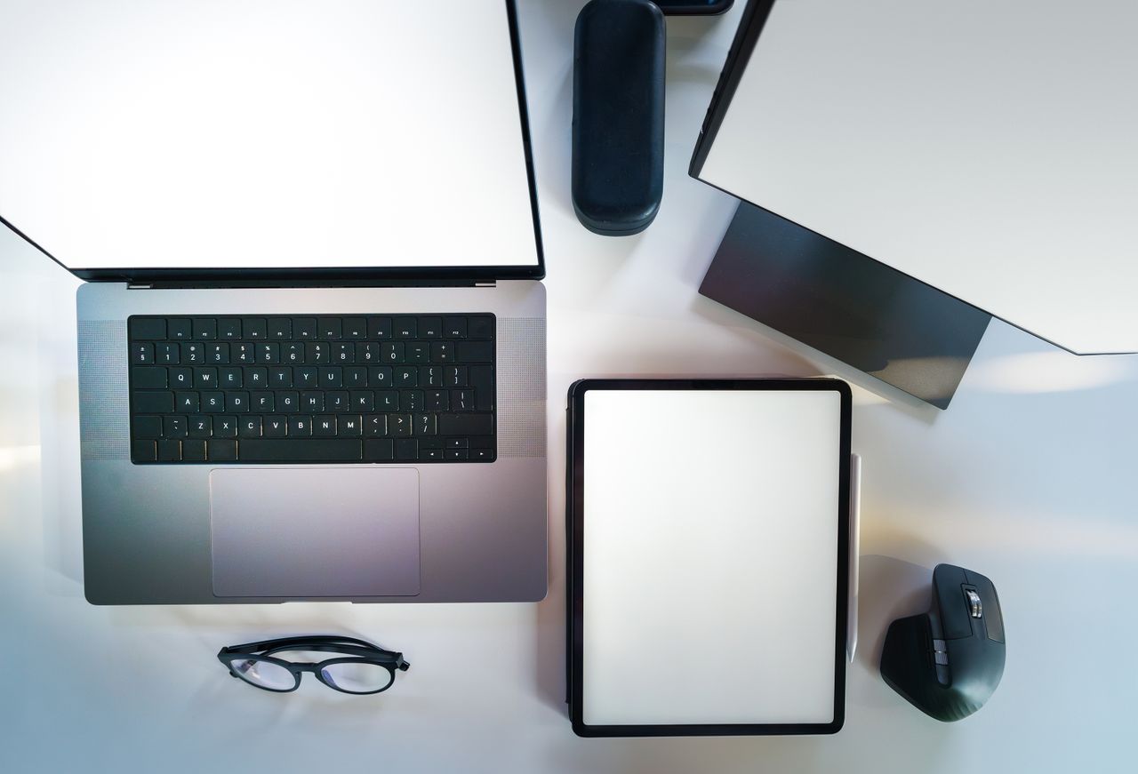 about-01 Top view of a sleek modern office desk with a laptop, tablet, and accessories.